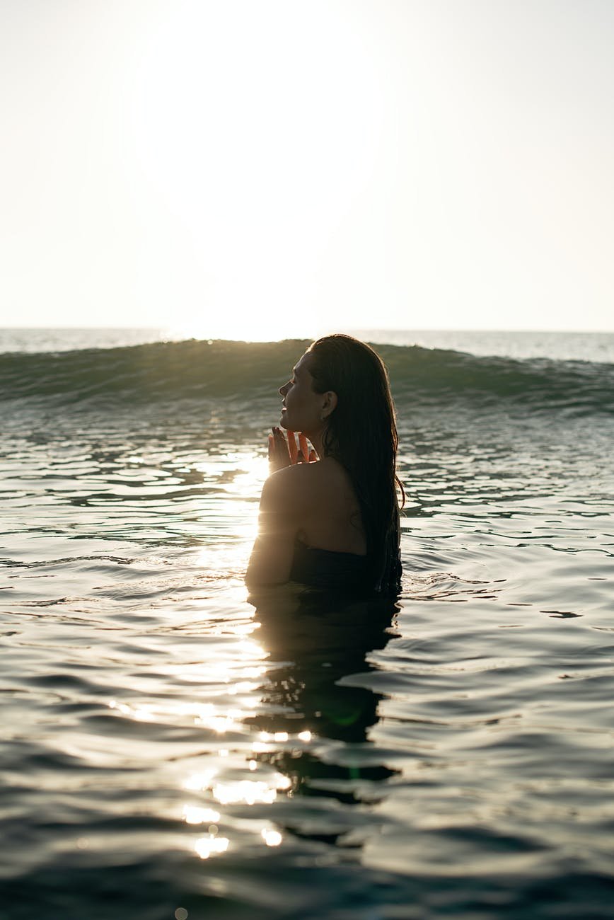 graceful young woman swimming in rippling sea at sundown